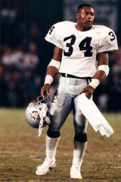 a football player standing on the field with his helmet and glove in hand while holding papers