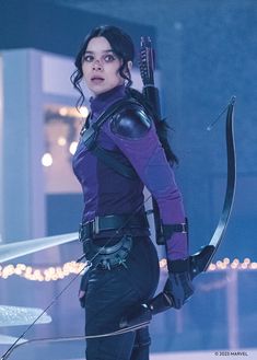 a woman dressed in purple holding a bow and arrow