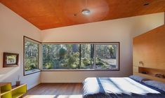 a bedroom with wood floors and a large window overlooking the woods in front of it