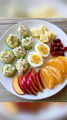 a white plate topped with sliced up fruit and veggies next to deviled eggs