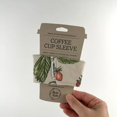 someone is holding up two coffee cup sleeves with strawberries and leaves printed on them