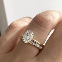 a woman's hand with a diamond ring on top of her finger and the engagement band