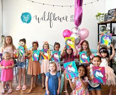 a group of children holding up paintings and balloons