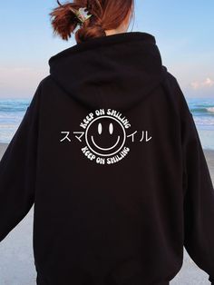 "Smiley face Keep on smiling Hoodie! Japanese word means \"smile.\" Aesthetic/Trendy Hoodie will be a perfect gift for yourself, friend's birthday, holiday gifts, etc... Model is size M, but in the picture is wearing size XL Gildan 18500 hoodie for an oversized look. A unisex heavy blend hooded sweatshirt is relaxation itself. The material is a thick blend of cotton and polyester. This makes for a plush, soft feel alongside warmth. It's also a great surface for printing. There are no side seams. Oversized Kawaii Hoodie For Streetwear, Oversized Kawaii Sweatshirt For Streetwear, Kawaii Streetwear Hoodie With Letter Print, Kawaii Hooded Sweatshirt With Graphic Print, Funny Crew Neck Hoodie For Streetwear, Funny Relaxed Fit Sweatshirt For Streetwear, Casual Long Sleeve Hoodie With Front And Back Print, Cute Black Hoodie With Graphic Print, Funny Long Sleeve Hoodie For Streetwear