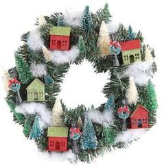 a christmas wreath with small houses and trees on the front, surrounded by white snow