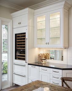 a kitchen filled with lots of white cabinets and counter top space next to a window