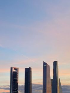 an airplane is flying in the sky over some tall buildings and water at sunset or dawn