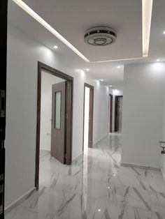 an empty white room with two doors and some lights on the ceiling is lit by recessed lighting