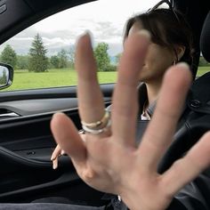 a woman making the v sign in her car with her hand up to the camera