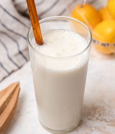 there is a glass of milk next to some lemons and cinnamon sticks on the table