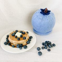 blueberries and pancakes on a plate next to a knitted pumpkin