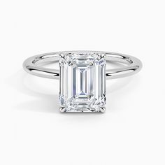 an emerald - cut diamond ring with two clawed shans on the shoulders and sides