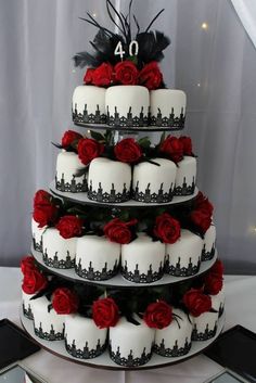 a three tiered cake with red roses on the bottom and black trimmings