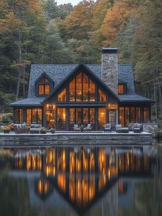 a large house sitting on top of a lake next to a forest filled with trees