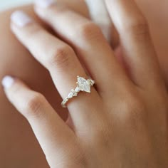 a woman's hand with a diamond ring on top of her left hand,