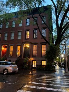 an apartment building on the corner of a city street at night with its lights on