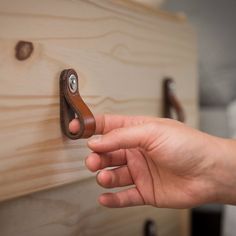 a person's hand holding a wooden drawer handle