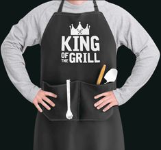 a man wearing an apron with the words king of the grill written on it and holding a spoon in his hand