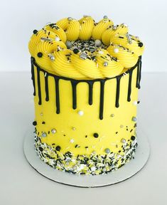 a yellow cake with black and white icing on the top is covered in sprinkles