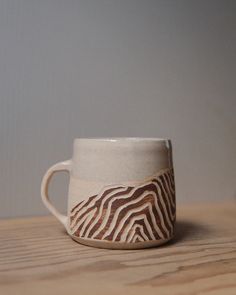 a white and brown cup sitting on top of a wooden table