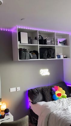 a bed with white sheets and purple lights on the headboard is in front of a gray wall