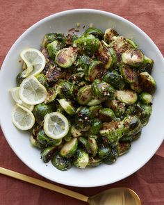 a white bowl filled with brussel sprouts and lemon slices