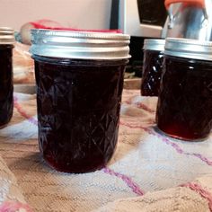 three jars of jam sitting on top of a table next to an orange and white towel