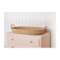 a wicker basket sitting on top of a pink dresser next to a white wall