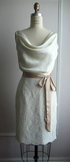 a white dress on a mannequin with a beige sash around the waist and neck