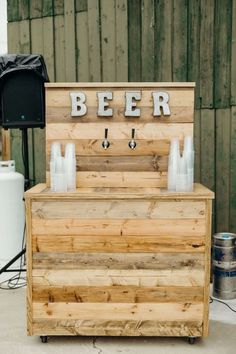 an outdoor bar made out of pallet wood with beer glasses on the top and bottom