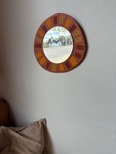 a mirror hanging on the side of a wall next to a chair and pillow in a room