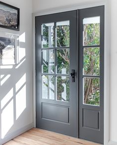 an empty room with two double doors and a window on the wall, in front of a wooden floor