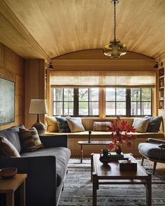 a living room filled with furniture and a large window covered in wooden paneled walls