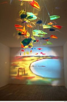 an art installation in a white room with multicolored objects hanging from the ceiling