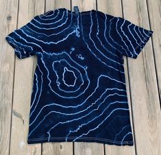 a blue t - shirt with white swirls on it sitting on a wooden floor