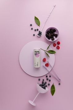 an assortment of fruits and berries on a pink surface with spoons, measuring cups and utensils