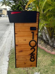 a wooden sign sitting on the side of a road next to a lush green field