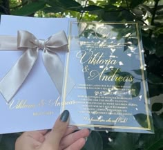 a person holding up a wedding card with a bow on the front and back of it