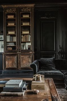 a living room filled with furniture and bookshelves in black walls, along with a wooden coffee table