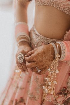 a woman in a pink lehenga holding her hands together