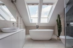 a white bath tub sitting under two skylights in a bathroom next to a toilet