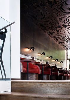 the interior of a restaurant with red chairs and black wallpaper on the walls, along with wooden steps