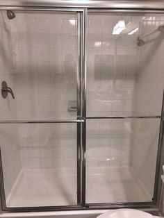 a white toilet sitting next to a shower in a bathroom with glass doors on it