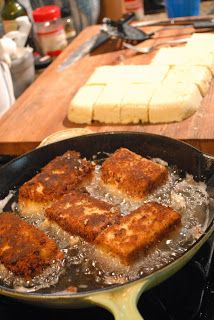 some food is cooking in a skillet on the stove with other items nearby, including bread and water