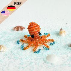 an orange octopus made out of beads sitting in the sand