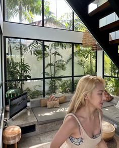 a woman sitting on top of a wooden floor next to a window filled with plants