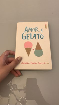 a hand holding an ice cream book on top of a white table with the title'amaror e gelato '