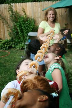 a group of children eating donuts in the back yard with their mother and grandmother