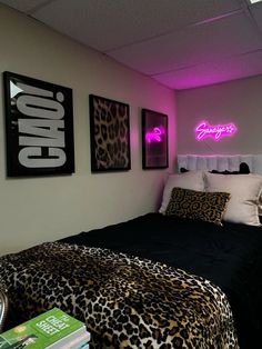 a bedroom with leopard print bedding and pink neon signs on the wall above it