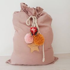 a pink bag with two pom poms and a star on the front is shown